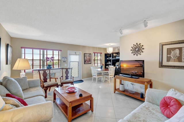 tiled living room featuring rail lighting and a textured ceiling