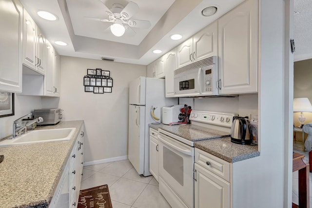 kitchen featuring white cabinetry, sink, a tray ceiling, white appliances, and light tile patterned flooring