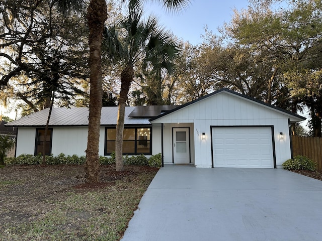 view of front of home featuring a garage, fence, metal roof, and concrete driveway