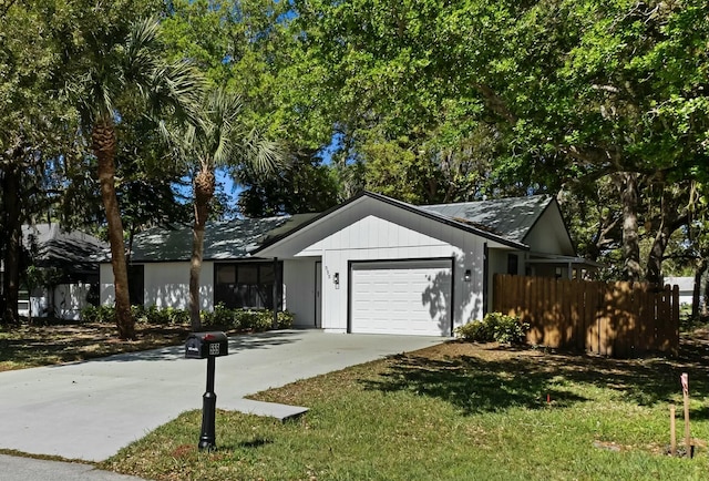 single story home with a garage, driveway, a front lawn, and fence