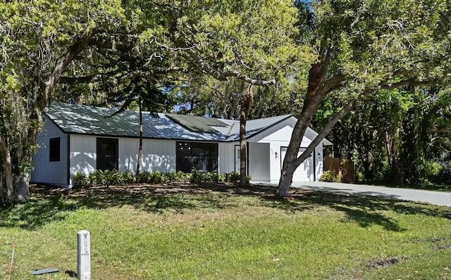 view of front of house with a garage, a front yard, driveway, and solar panels