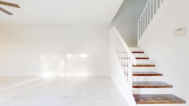 stairway featuring marble finish floor, a ceiling fan, and baseboards