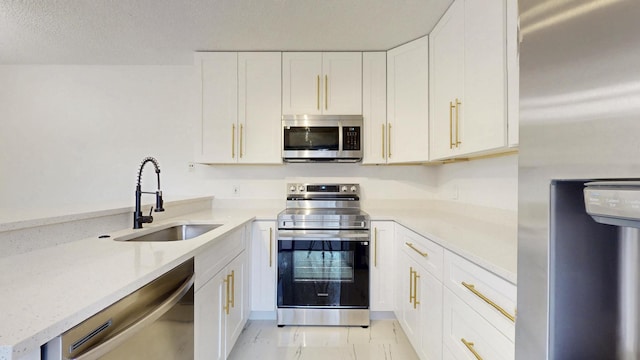 kitchen featuring stainless steel appliances, white cabinets, a sink, and light stone counters