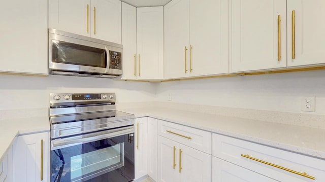 kitchen featuring appliances with stainless steel finishes, white cabinetry, and light stone counters