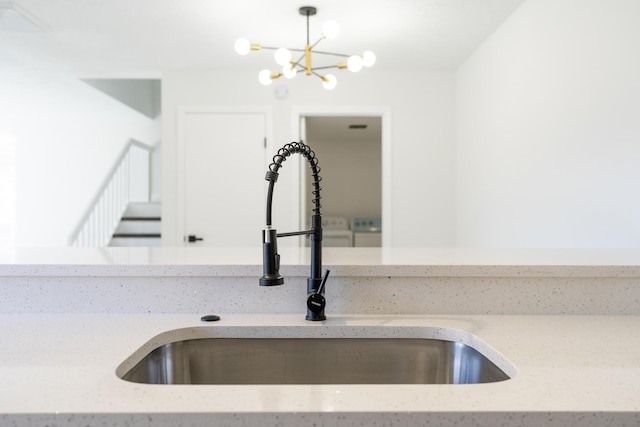 room details featuring hanging light fixtures, light stone counters, and a sink