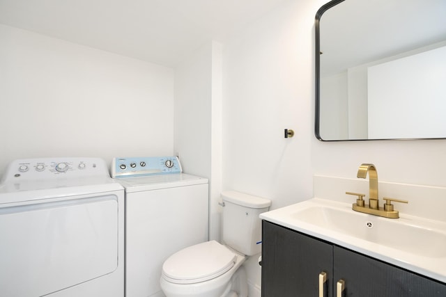 bathroom with toilet, washer and clothes dryer, and vanity