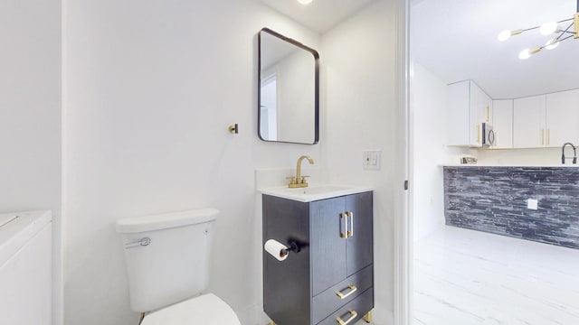 bathroom with toilet, washer and dryer, and vanity