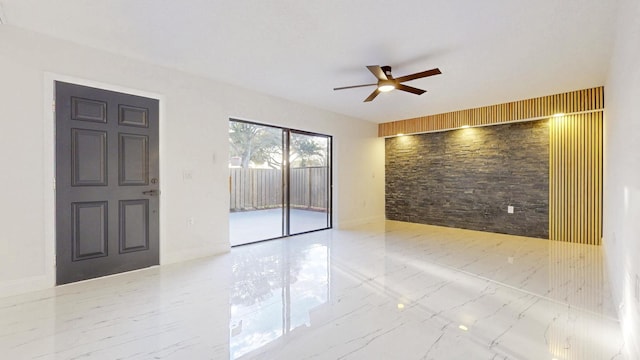 unfurnished room with marble finish floor, baseboards, and a ceiling fan