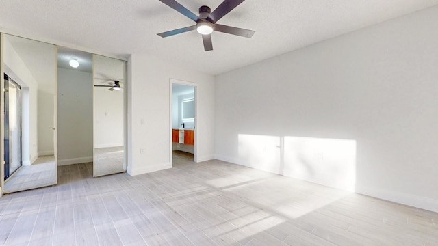 unfurnished bedroom with a textured ceiling, light wood-type flooring, a ceiling fan, and baseboards