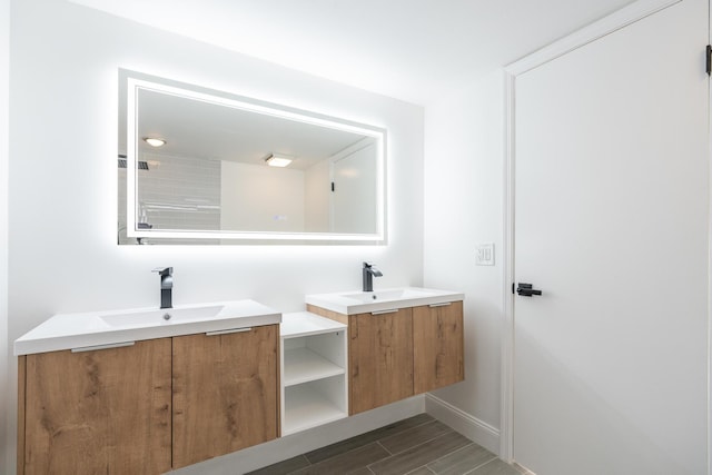 bathroom with baseboards, two vanities, and a sink