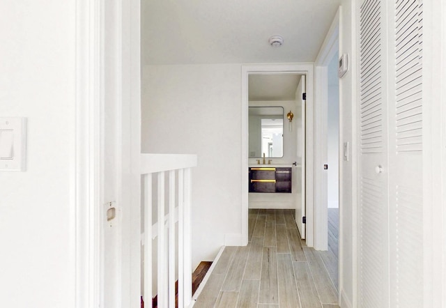 corridor featuring light wood-style flooring and a sink