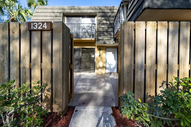 view of exterior entry with a gate, fence, and mansard roof