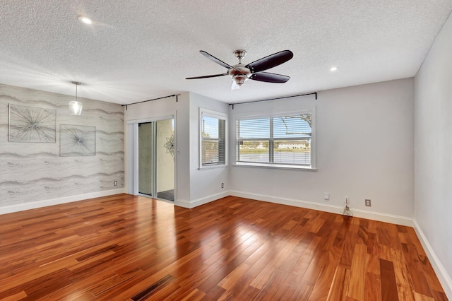 spare room with a textured ceiling, ceiling fan, and wood-type flooring