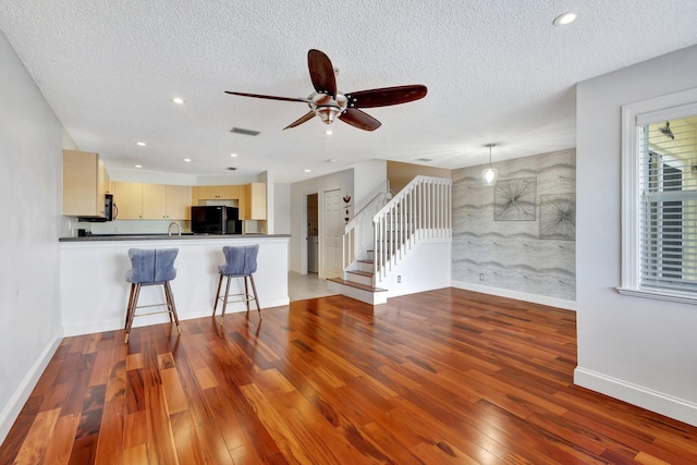 unfurnished living room featuring sink, hardwood / wood-style flooring, a textured ceiling, and ceiling fan