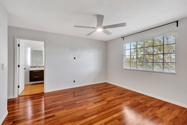 unfurnished bedroom featuring ensuite bath, a textured ceiling, ceiling fan, hardwood / wood-style floors, and sink