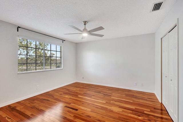 unfurnished bedroom with hardwood / wood-style flooring, ceiling fan, a textured ceiling, and a closet