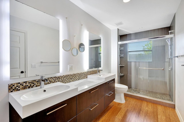 bathroom featuring wood-type flooring, vanity, a shower with door, and toilet