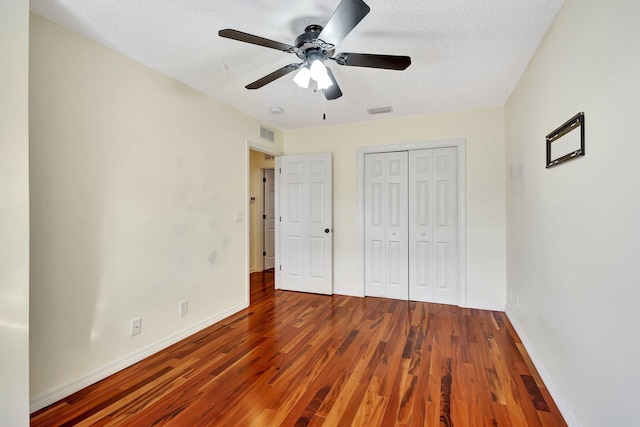 unfurnished bedroom featuring ceiling fan, a closet, wood-type flooring, and a textured ceiling