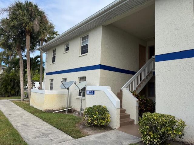 view of home's exterior with stairs and stucco siding