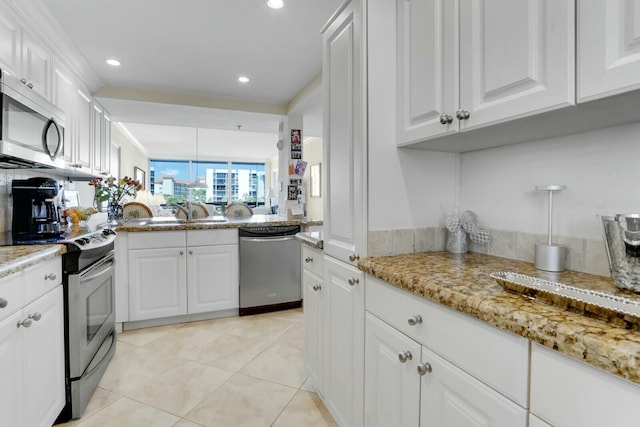 kitchen with appliances with stainless steel finishes, light stone countertops, sink, and white cabinets