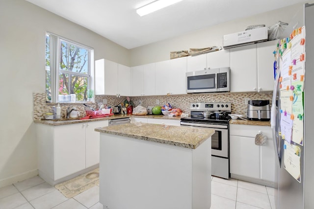 kitchen featuring appliances with stainless steel finishes, white cabinets, a kitchen island, and tasteful backsplash