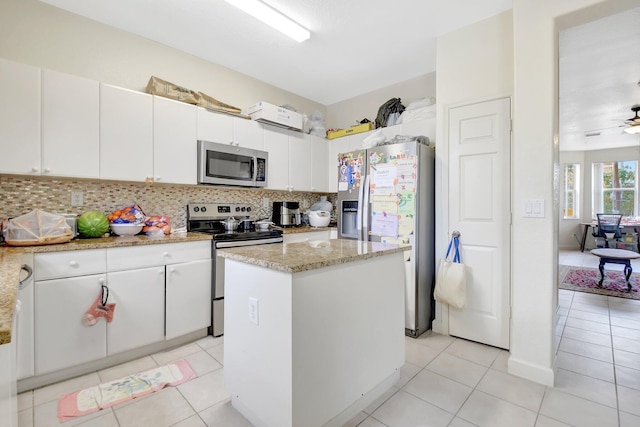 kitchen featuring stainless steel appliances, white cabinets, a kitchen island, and decorative backsplash