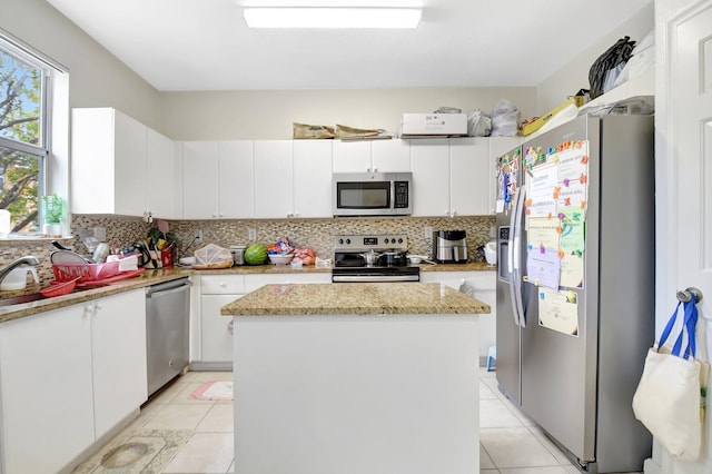 kitchen with appliances with stainless steel finishes, decorative backsplash, white cabinetry, and a center island