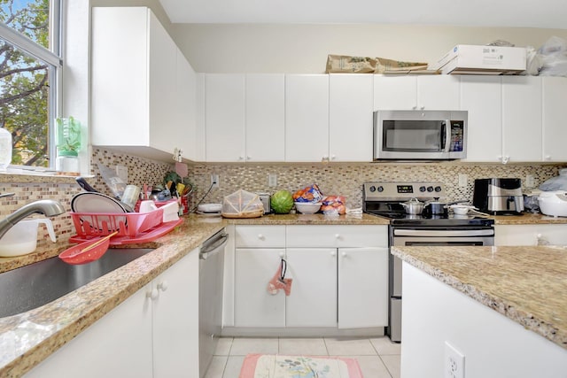 kitchen with appliances with stainless steel finishes, decorative backsplash, a sink, and white cabinets