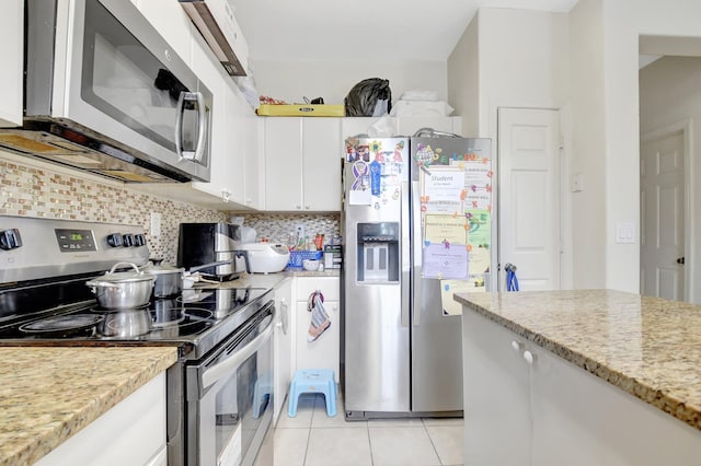 kitchen with tasteful backsplash, appliances with stainless steel finishes, light stone counters, white cabinetry, and light tile patterned flooring