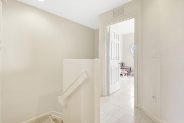 hall with visible vents, light tile patterned floors, an upstairs landing, and baseboards