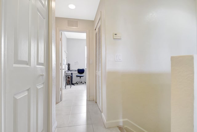 hall featuring baseboards, visible vents, and light tile patterned flooring