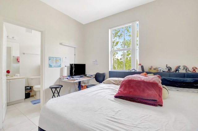 bedroom featuring ensuite bathroom and light tile patterned flooring