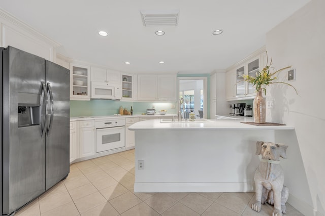 kitchen with white cabinetry, sink, light tile patterned floors, kitchen peninsula, and white appliances