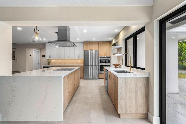 kitchen with appliances with stainless steel finishes, pendant lighting, island range hood, white cabinetry, and sink