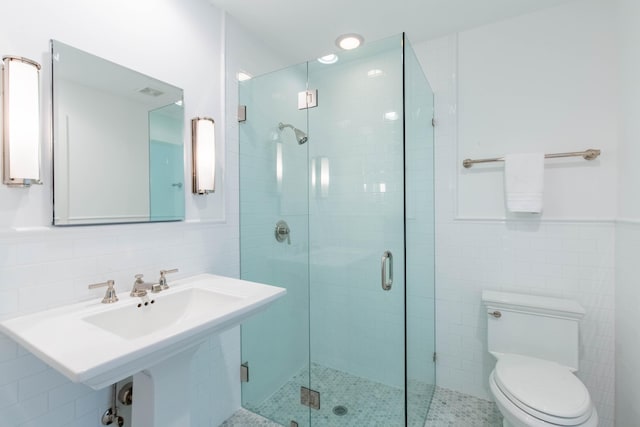 bathroom with a shower stall, wainscoting, tile walls, and toilet