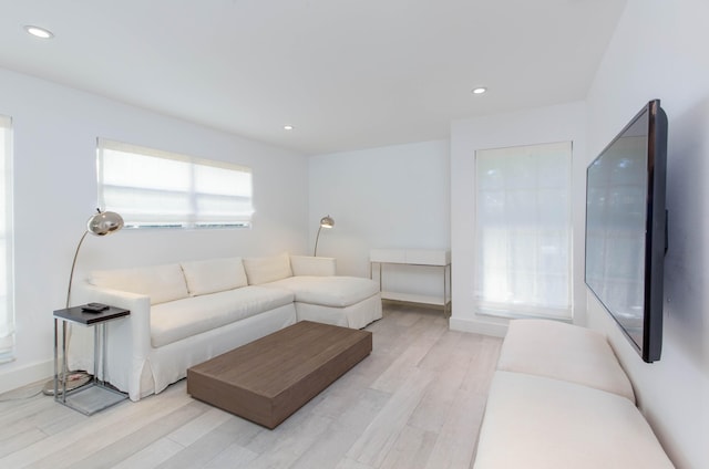 living area featuring baseboards, light wood finished floors, and recessed lighting