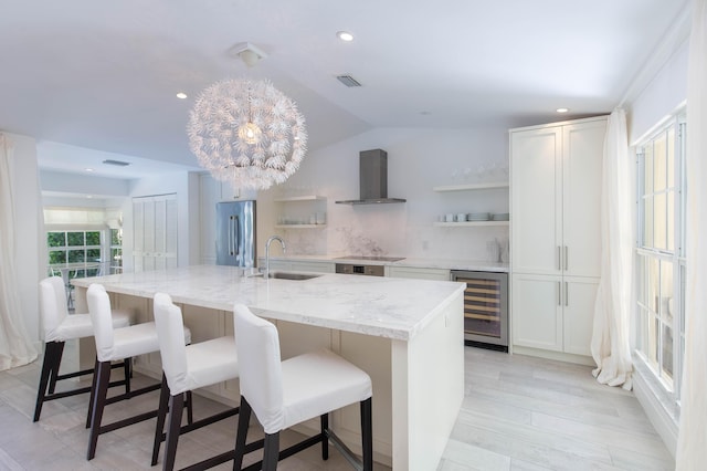 kitchen with wine cooler, open shelves, a sink, wall chimney exhaust hood, and stainless steel refrigerator