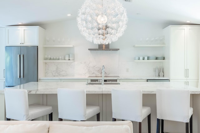 kitchen with open shelves, light stone counters, stainless steel refrigerator, and white cabinets