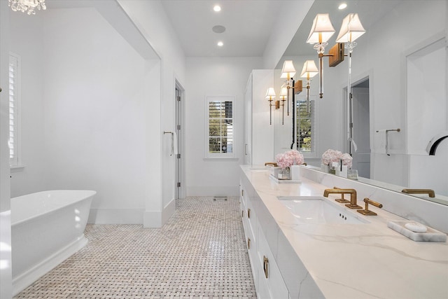 bathroom featuring vanity, a bath, and a chandelier