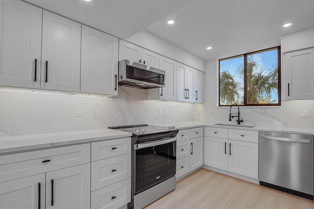 kitchen featuring white cabinetry, sink, light wood-type flooring, and appliances with stainless steel finishes