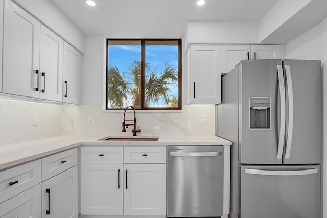 kitchen with backsplash, stainless steel appliances, sink, and white cabinets