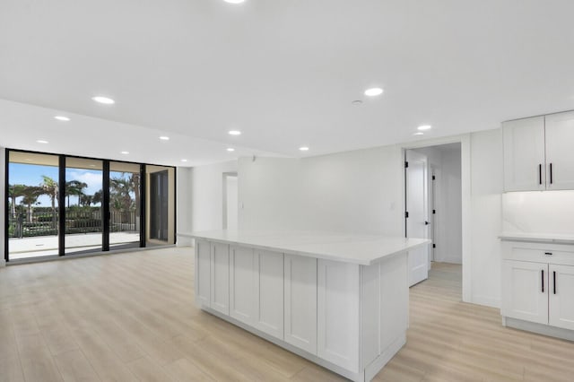 kitchen featuring white cabinetry, floor to ceiling windows, a center island, and light hardwood / wood-style flooring