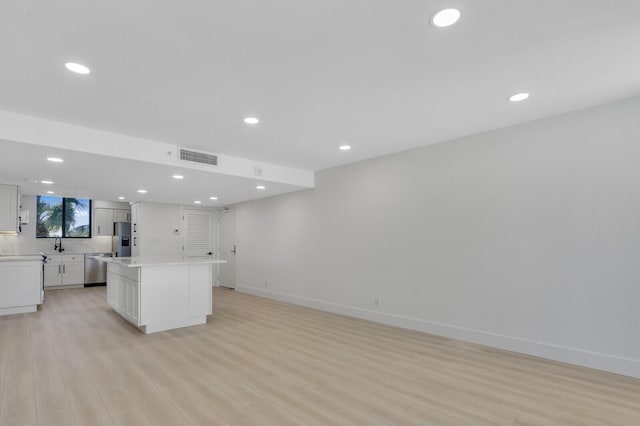 kitchen featuring sink, light hardwood / wood-style flooring, appliances with stainless steel finishes, white cabinets, and a kitchen island