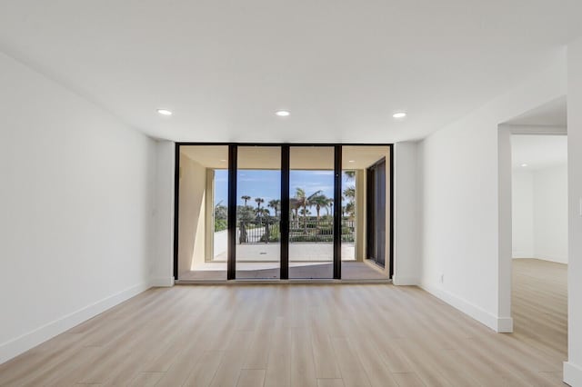 spare room featuring floor to ceiling windows and light hardwood / wood-style flooring