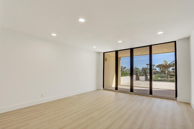 spare room featuring a wall of windows and light hardwood / wood-style floors