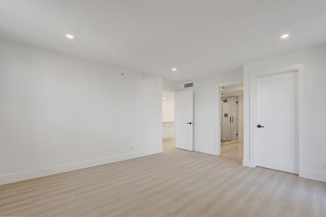 unfurnished bedroom with ensuite bath and light hardwood / wood-style flooring