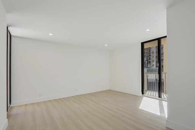 spare room featuring expansive windows and light hardwood / wood-style flooring