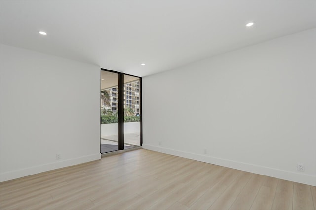 empty room with floor to ceiling windows and light hardwood / wood-style floors