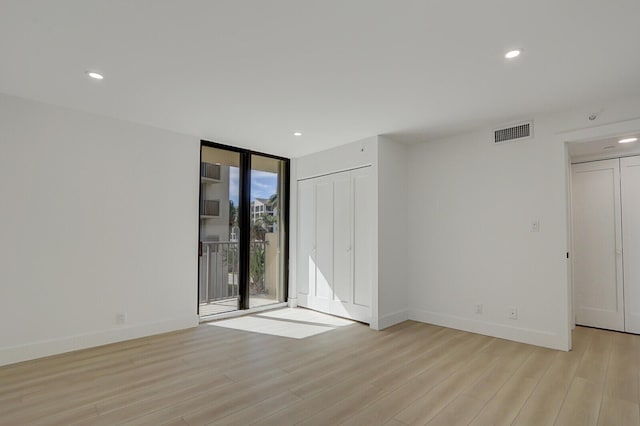 spare room with light hardwood / wood-style floors and expansive windows