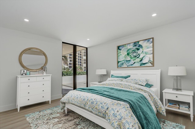 bedroom with floor to ceiling windows, access to outside, and dark hardwood / wood-style flooring